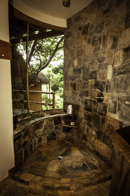 Ensuite bathroom with stone shower with outdoor ocean views.