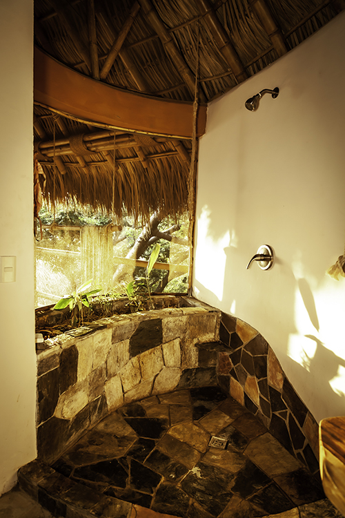 Ensuite bathroom with stone shower with outdoor ocean views.