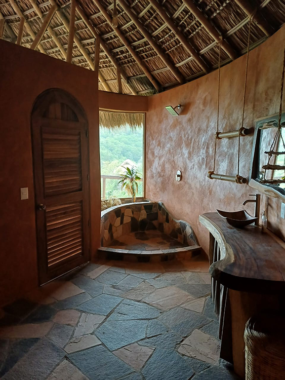 Ensuite bathroom with stone shower with outdoor ocean views.