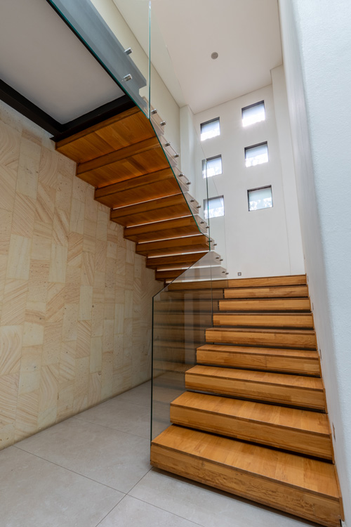 wooden stairwell with glass banister